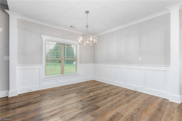 unfurnished room with hardwood / wood-style floors, ornamental molding, and a notable chandelier