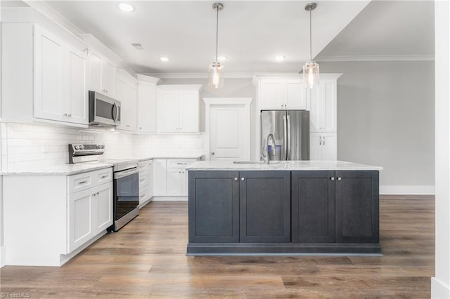 kitchen with white cabinets, stainless steel appliances, hanging light fixtures, and an island with sink