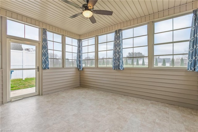 unfurnished sunroom featuring a healthy amount of sunlight, ceiling fan, and wood ceiling