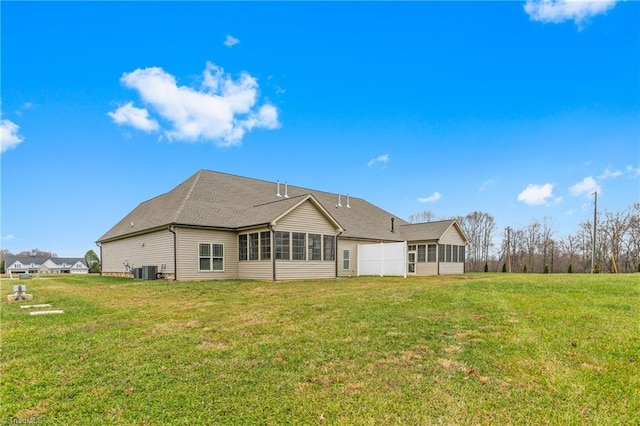 back of property featuring a sunroom, central AC unit, and a lawn