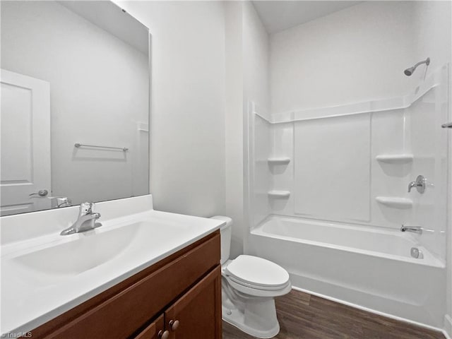 full bath featuring toilet, wood finished floors, vanity, and washtub / shower combination