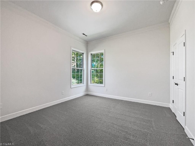 empty room featuring baseboards, dark carpet, visible vents, and crown molding