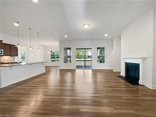 unfurnished living room with a fireplace with flush hearth, dark wood-style floors, and recessed lighting
