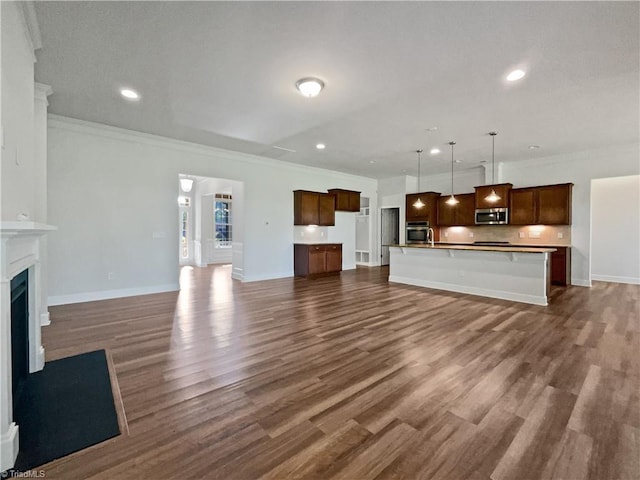 unfurnished living room featuring dark wood-type flooring, a fireplace, ornamental molding, and recessed lighting