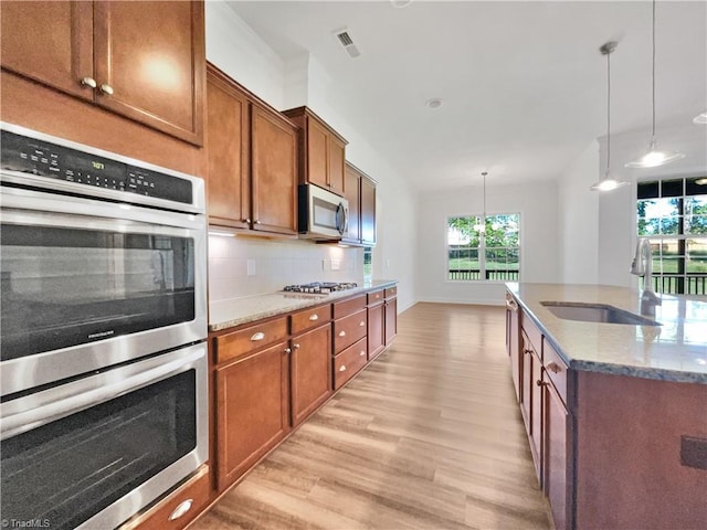 kitchen with light wood finished floors, a wealth of natural light, appliances with stainless steel finishes, and a sink