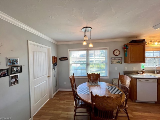 dining room with ornamental molding, sink, and light hardwood / wood-style floors