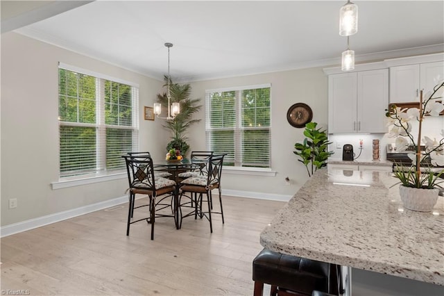 dining space with light hardwood / wood-style flooring and crown molding