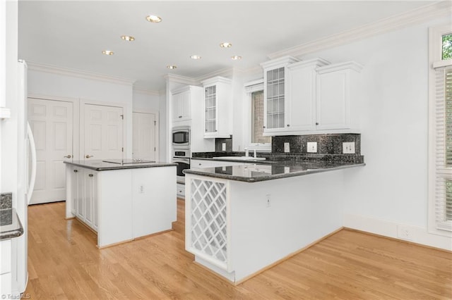 1000 Brookmeade Dr, Winston-Salem, NC 27106 - kitchen with appliances with stainless steel finishes, ornamental molding, white cabinets, a center island, and light wood-style floors