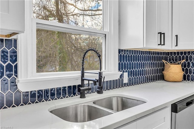 kitchen featuring tasteful backsplash, light stone countertops, dishwasher, white cabinetry, and a sink