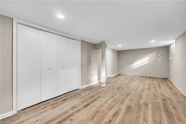 finished basement with concrete block wall, recessed lighting, baseboards, and light wood finished floors