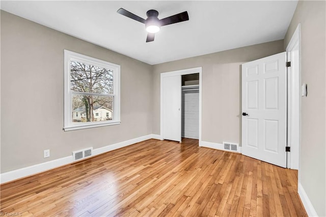 unfurnished bedroom featuring light wood-type flooring, visible vents, baseboards, and a closet