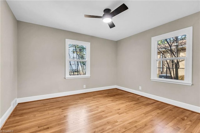 unfurnished room featuring light wood finished floors, visible vents, a ceiling fan, and baseboards