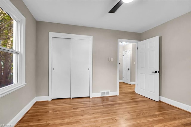 unfurnished bedroom featuring multiple windows, baseboards, visible vents, and light wood finished floors