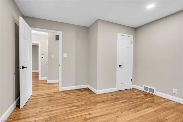 empty room featuring visible vents, light wood-type flooring, and baseboards