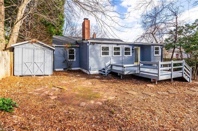 rear view of property with fence, a chimney, an outdoor structure, a deck, and a storage shed