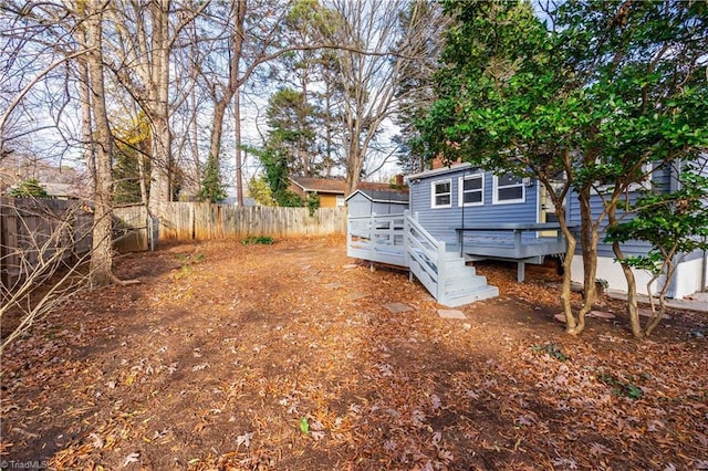 exterior space featuring a fenced backyard, a deck, a storage shed, and an outdoor structure