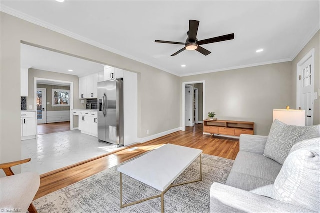 living area with ceiling fan, baseboards, ornamental molding, recessed lighting, and light wood-style floors