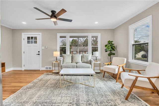 living room featuring baseboards, a healthy amount of sunlight, visible vents, and light wood-type flooring