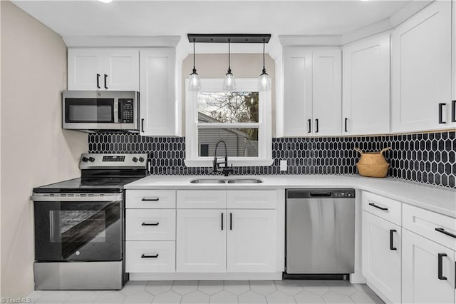 kitchen featuring light countertops, decorative backsplash, appliances with stainless steel finishes, white cabinetry, and a sink