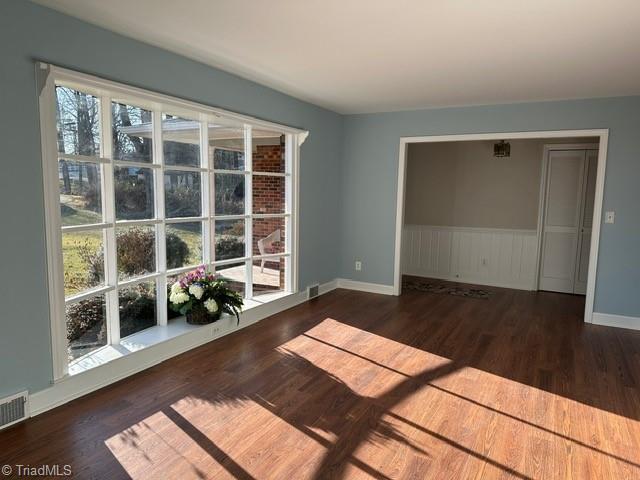 unfurnished room featuring a healthy amount of sunlight and dark hardwood / wood-style flooring