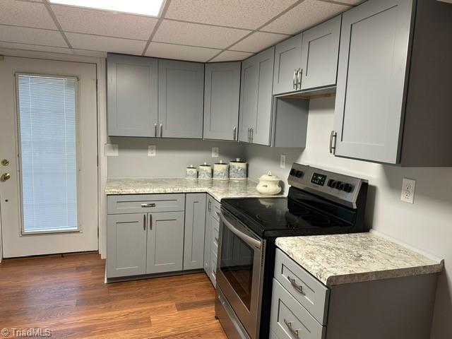 kitchen with gray cabinets, a paneled ceiling, light hardwood / wood-style floors, and electric stove