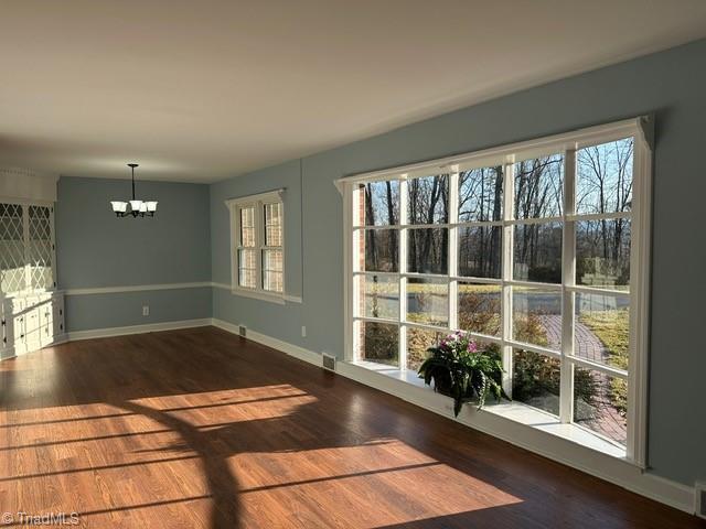 unfurnished dining area featuring dark hardwood / wood-style floors and a chandelier