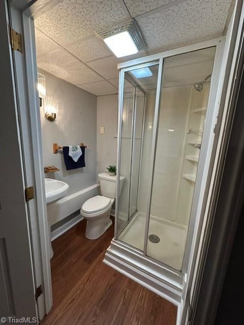 bathroom featuring a paneled ceiling, toilet, an enclosed shower, and hardwood / wood-style floors