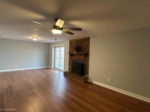 unfurnished living room featuring dark wood-type flooring, a fireplace, and ceiling fan