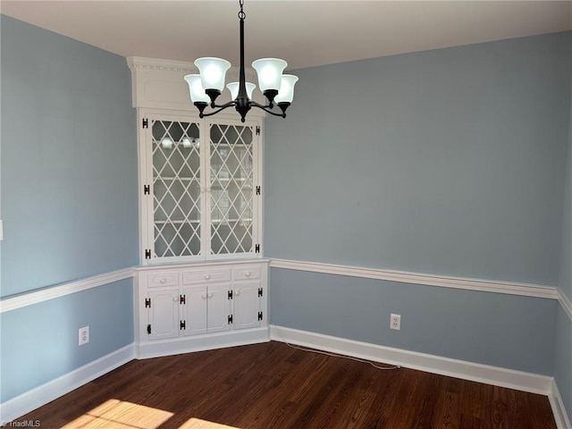 empty room with hardwood / wood-style floors and a chandelier