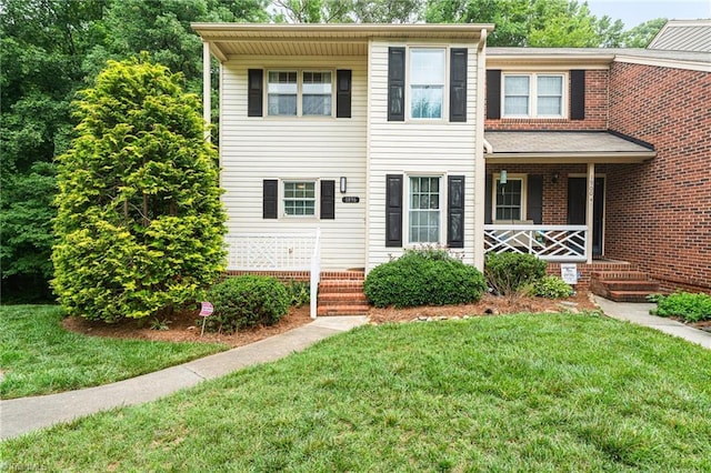 1896 Winds Dr, Winston-Salem, NC 27127 - view of front facade with a porch, a front lawn, and brick siding
