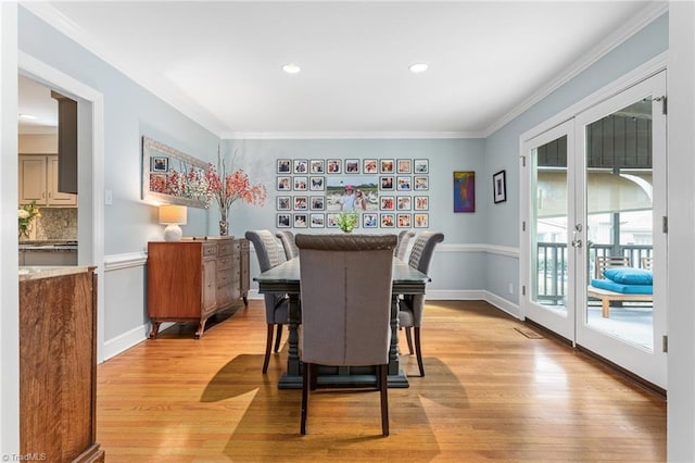 dining space featuring light wood finished floors, french doors, baseboards, and crown molding