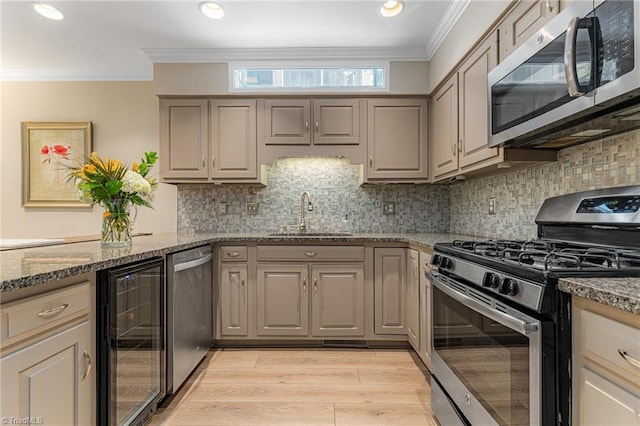 kitchen with beverage cooler, appliances with stainless steel finishes, a sink, and ornamental molding