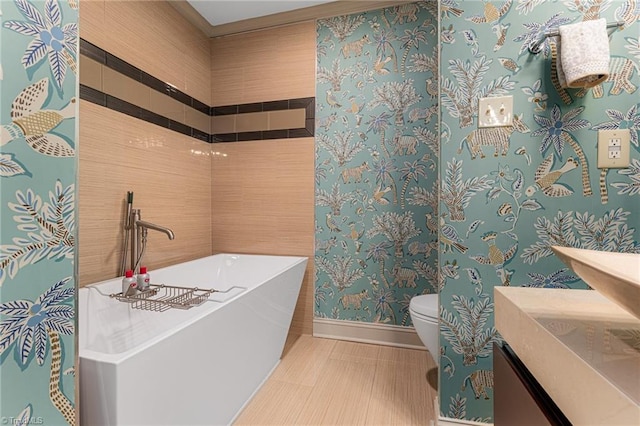 bathroom featuring toilet, vanity, baseboards, a soaking tub, and wallpapered walls