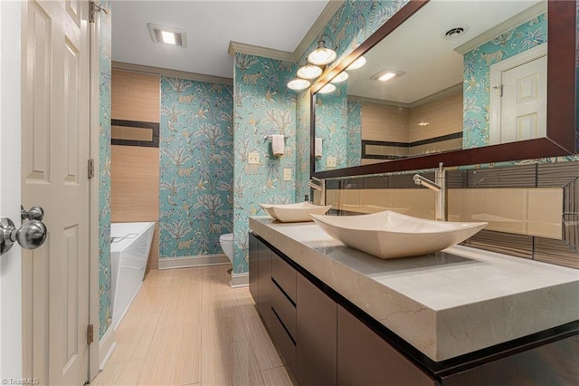 bathroom featuring wallpapered walls, a bathing tub, baseboards, and a sink