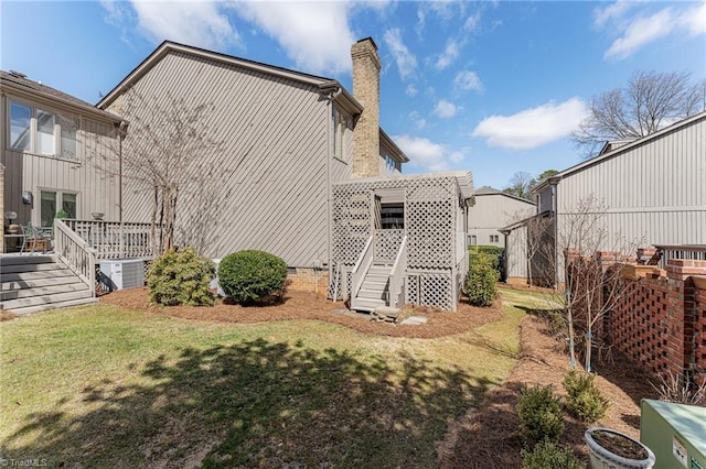 rear view of house featuring a chimney, a lawn, a deck, and central air condition unit