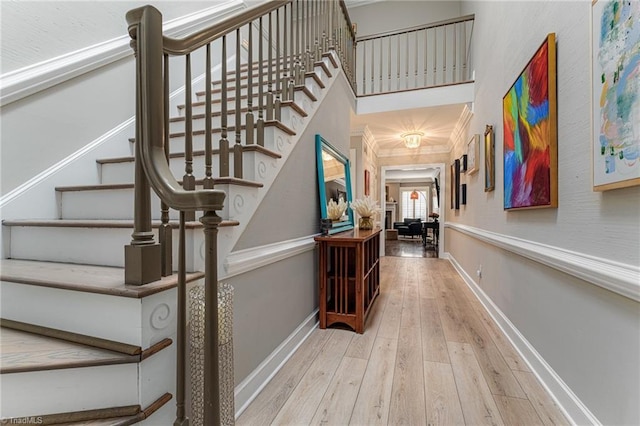 interior space with wood-type flooring, a towering ceiling, and baseboards