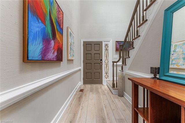 entryway featuring light wood-style flooring, stairs, and baseboards