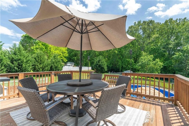 deck featuring fence, a storage unit, an outdoor pool, outdoor dining area, and an outdoor structure