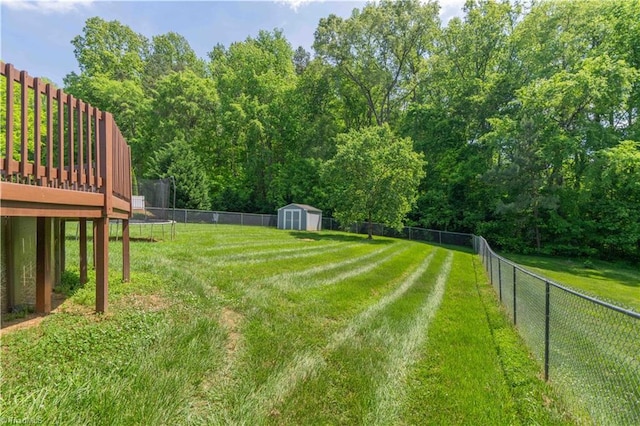 view of yard featuring a storage unit, a fenced backyard, an outbuilding, and a deck