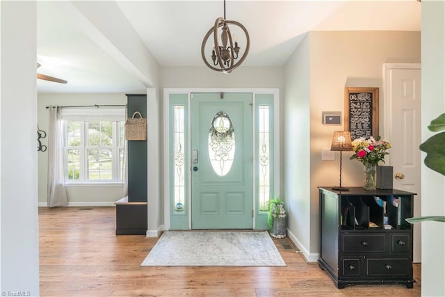 foyer entrance featuring an inviting chandelier, baseboards, and wood finished floors