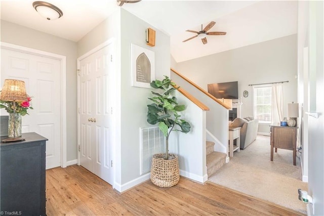 foyer with visible vents, wood finished floors, baseboards, ceiling fan, and stairway