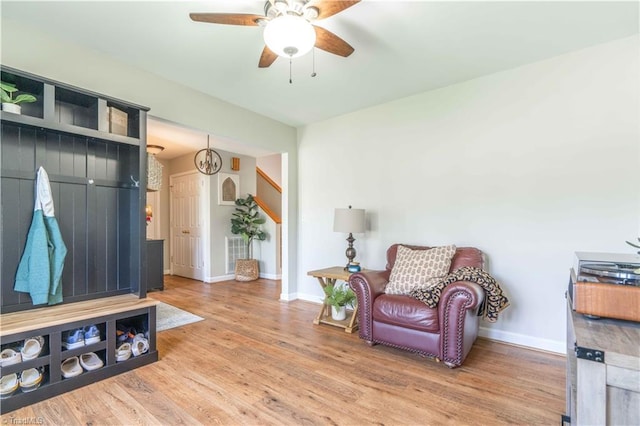 living area featuring baseboards, a ceiling fan, and wood finished floors