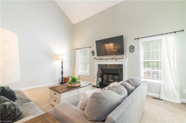 living area with light colored carpet, a fireplace, high vaulted ceiling, baseboards, and visible vents