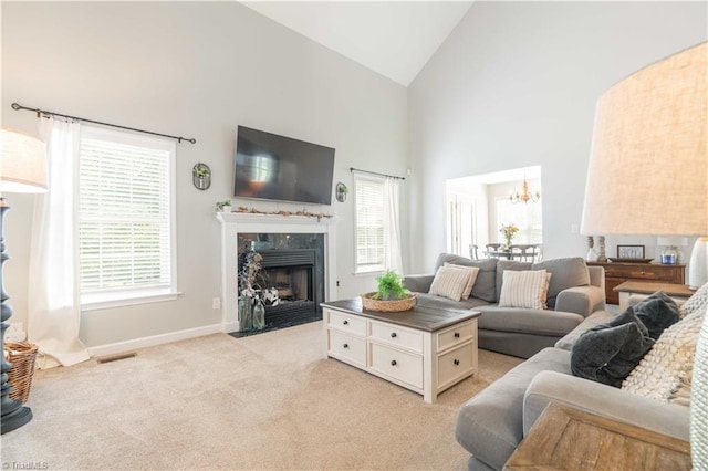 living area featuring a premium fireplace, visible vents, a healthy amount of sunlight, and an inviting chandelier