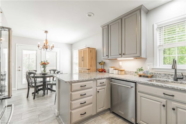 kitchen featuring stainless steel dishwasher, an inviting chandelier, a peninsula, gray cabinets, and a sink