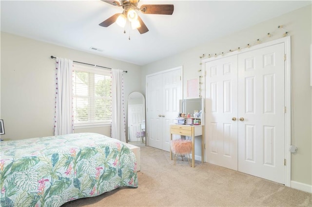 carpeted bedroom with baseboards, ceiling fan, two closets, and visible vents