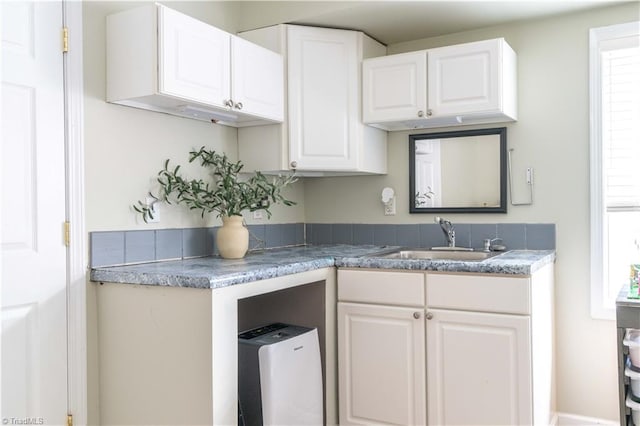 kitchen featuring white cabinets, a healthy amount of sunlight, and a sink