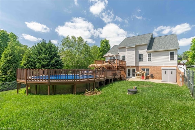 rear view of house with a fenced backyard, a fenced in pool, a lawn, and a deck