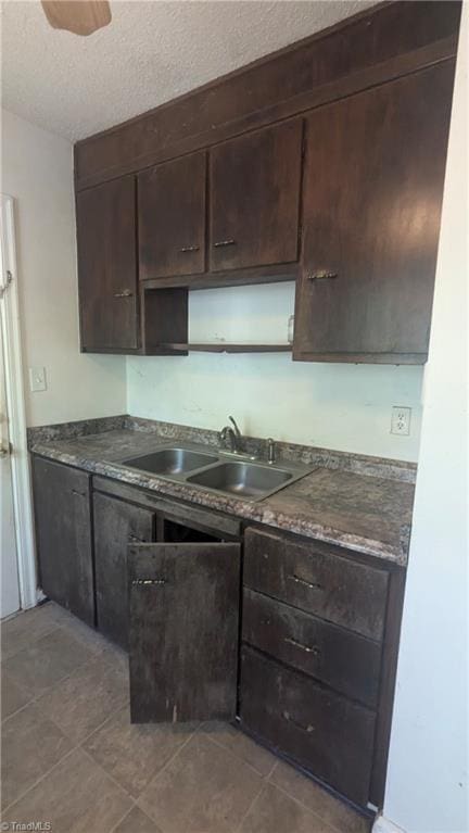 2806 Robin Hood Dr, Greensboro, NC 27408 - kitchen with dark brown cabinetry, dark countertops, a sink, and a textured ceiling