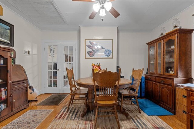 dining space with ceiling fan, light wood-type flooring, ornamental molding, and french doors